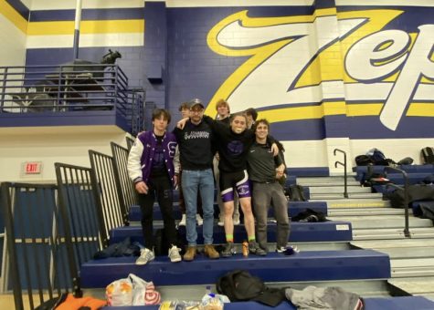 Student athletes pose with coaches on bleachers.